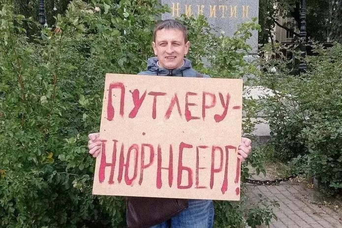 <em>Григорий Северин в одиночном пикете. За этот же плакат в январе 2021 года его <a href="https://ovd.info/express-news/2021/01/20/voronezhca-arestovali-iz-za-odinochnogo-piketa-v-podderzhku-navalnogo"><u>арестовали</u></a> на пять суток (ч. 8 ст. 20.2 КоАП РФ) / Фото: Свободные Люди Воронежа</em>